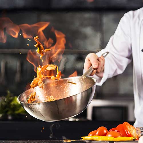 Koch Hände halten Wok mit Feuer. Closeup Koch Hände kochen Essen mit Feuer.